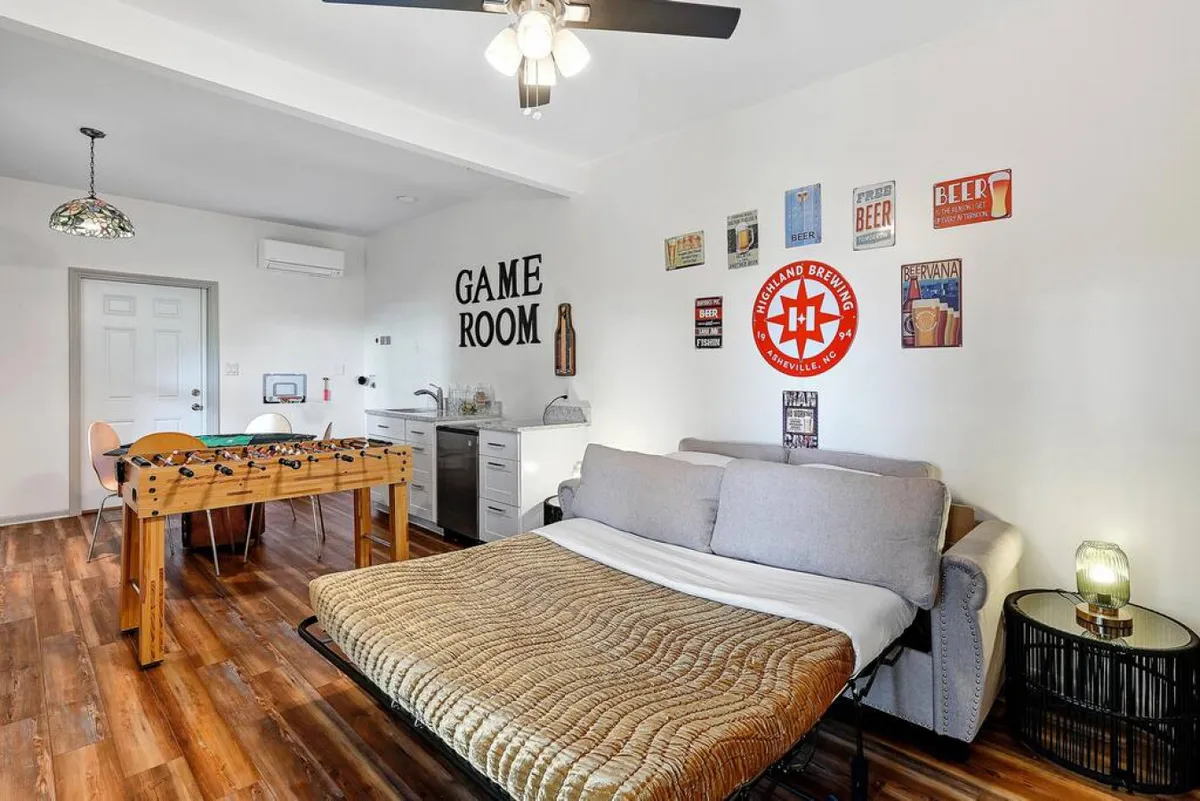 A cozy living area with a sleeper sofa, game table, and stylish wall decor. The space is arranged for comfort and easy conversation, ideal for relaxing or hosting group activities.