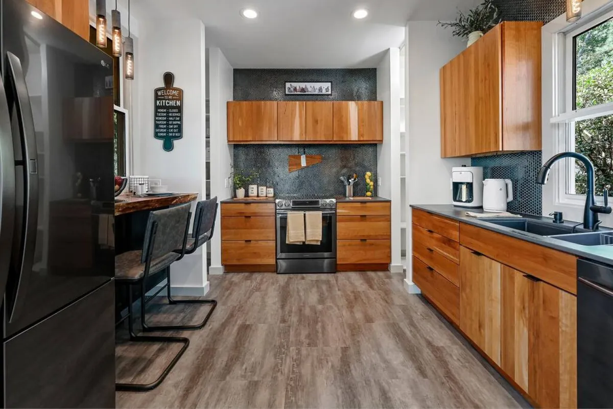 This image spotlights a spacious kitchen with a large island, stainless steel appliances, wooden cabinetry, and a decorative backsplash. The setting is warm and welcoming, perfectly set up for cooking, meal prep, and hosting gatherings.