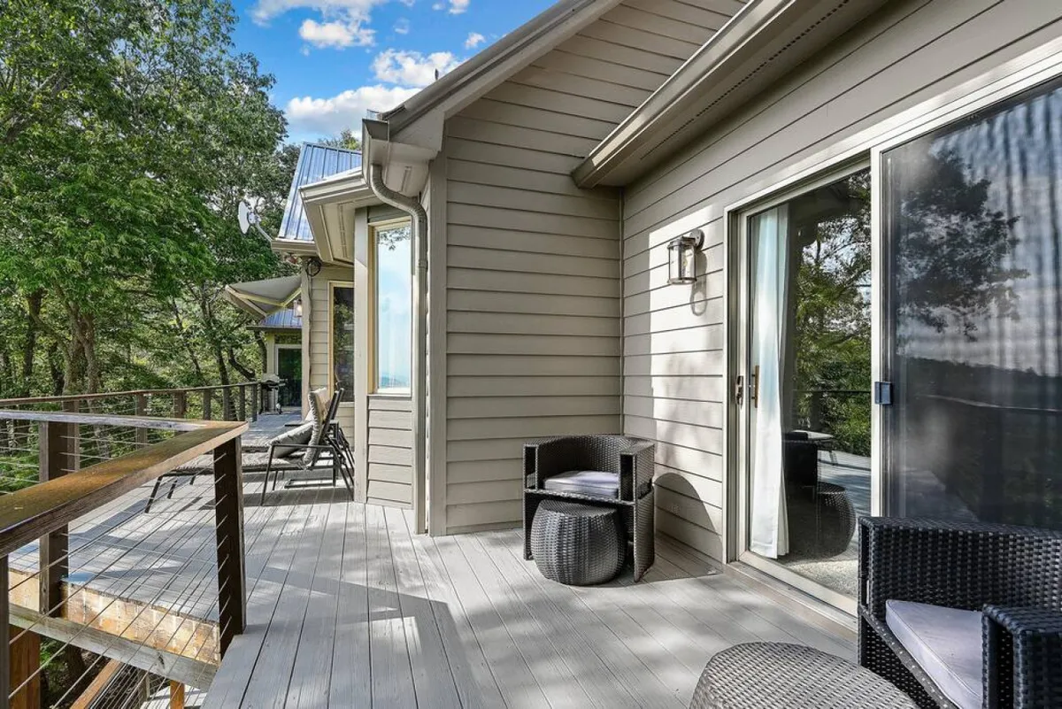 This image highlights a peaceful deck area with outdoor seating surrounded by tall trees, creating a secluded and calming atmosphere. The natural wood and cozy arrangement invite guests to relax and take in the fresh mountain air.